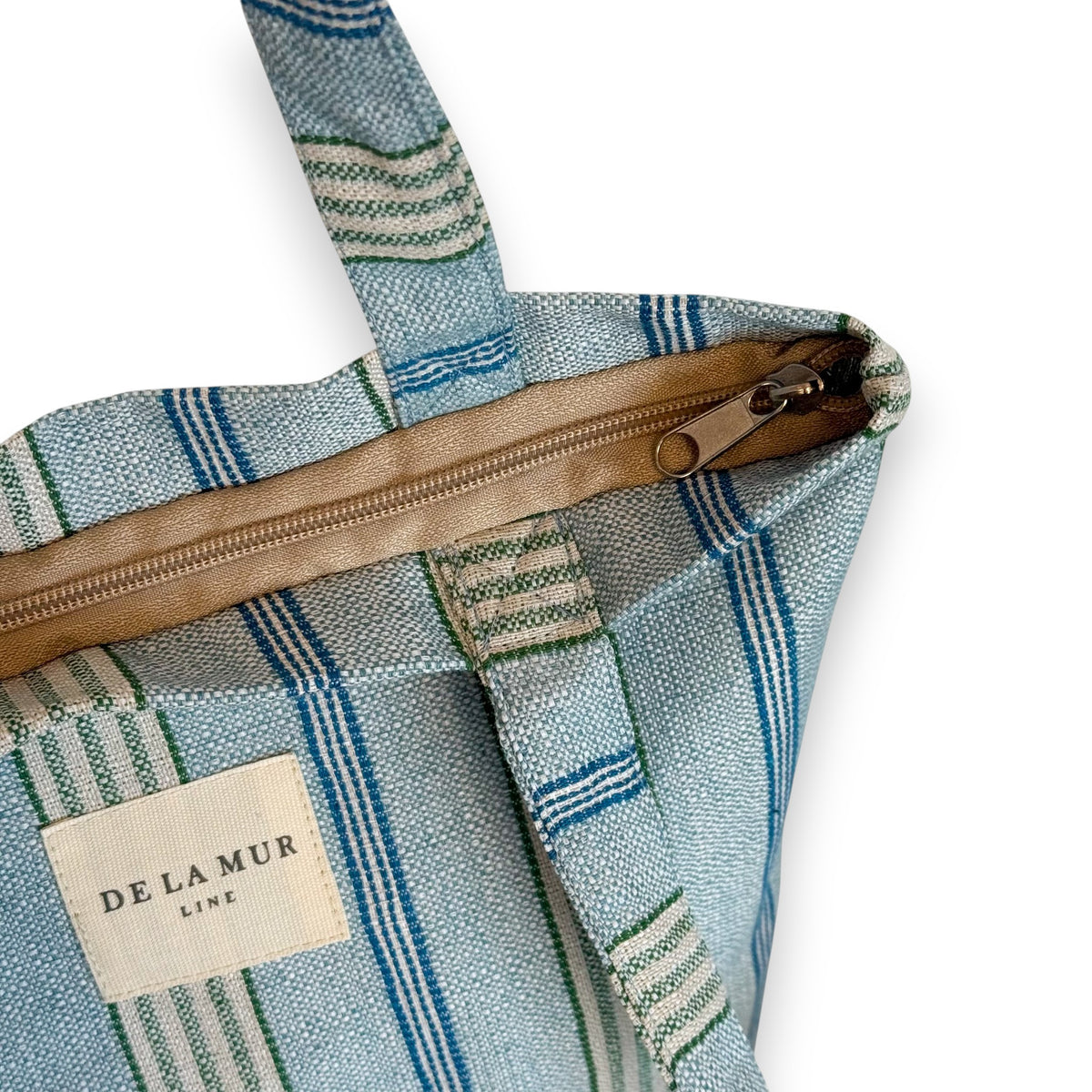 Open DE LA MUR striped bag showing zip closure and inner label