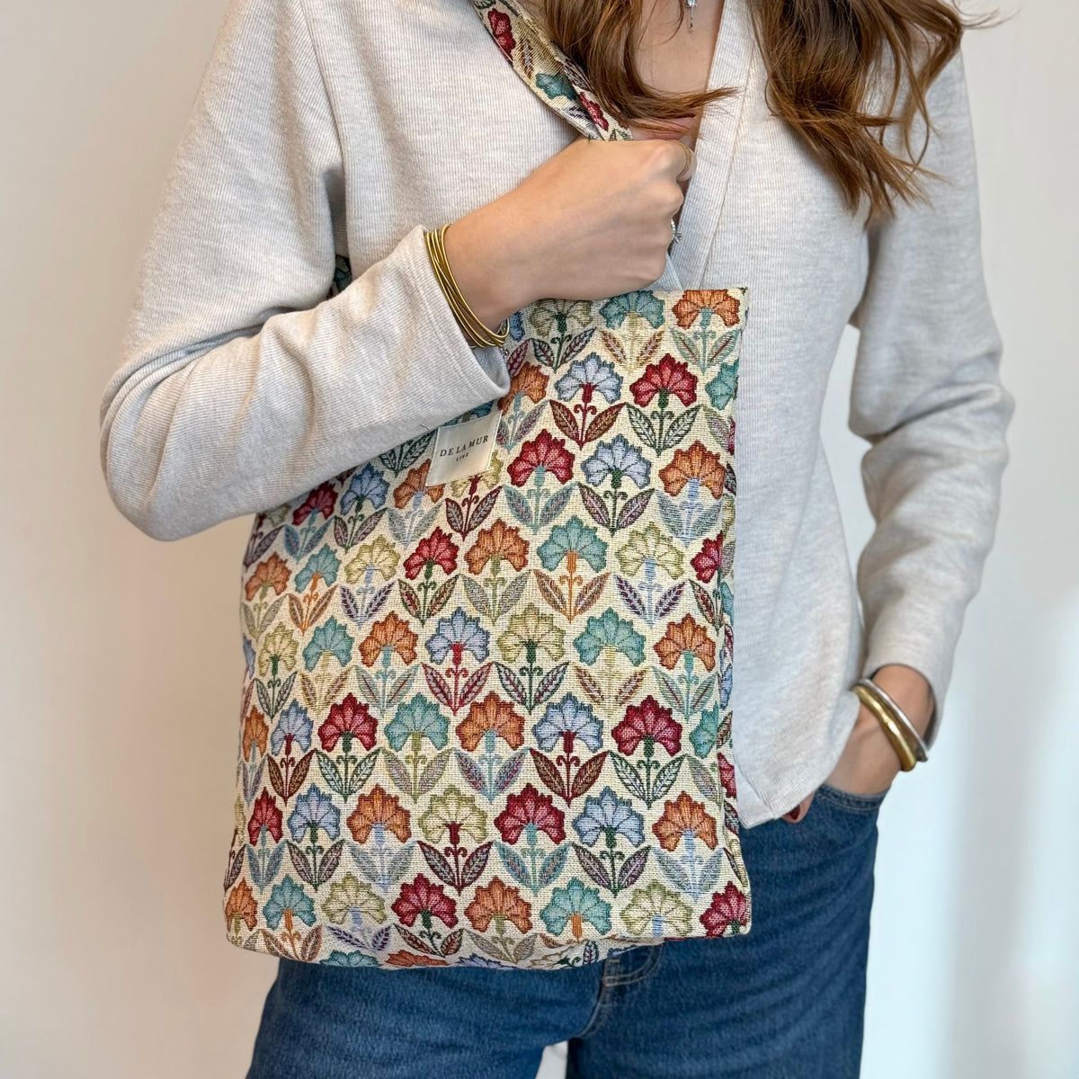 Model holding the DE LA MUR Flora multicolor floral zippered bag