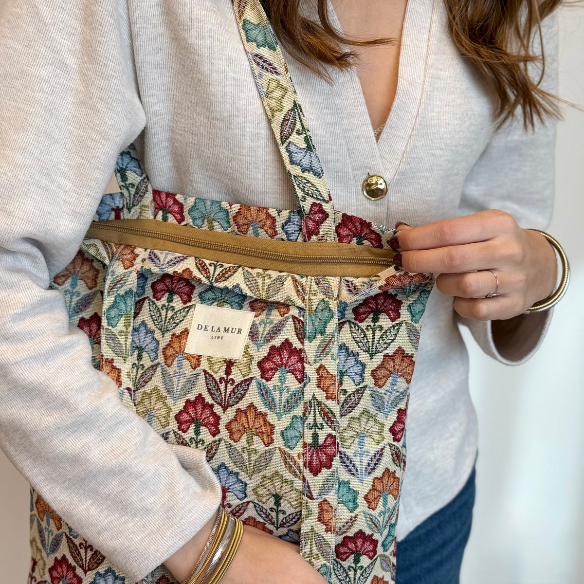 Model opening the DE LA MUR Flora bag, showing the lined interior