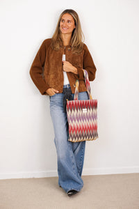 Model wearing DE LA MUR Guana zigzag jacquard zippered bag over the shoulder, lifestyle shot