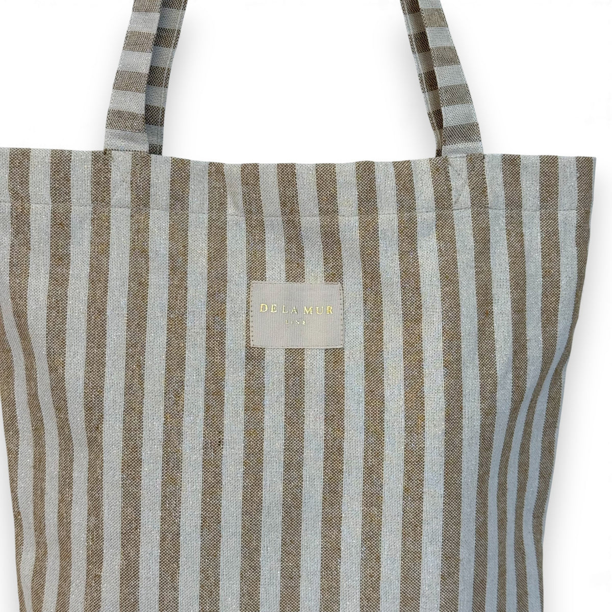 Close-up of the DE LA MUR Lumos mustard striped fabric and gold Line label