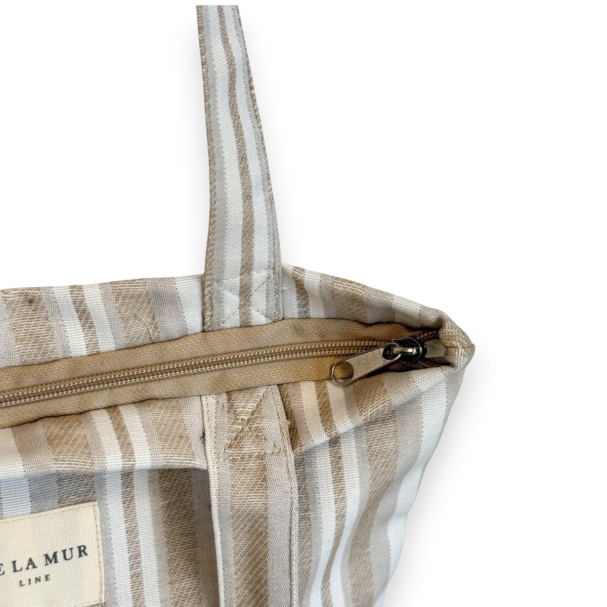 Model carrying the beige striped DE LA MUR Malik bag over the shoulder