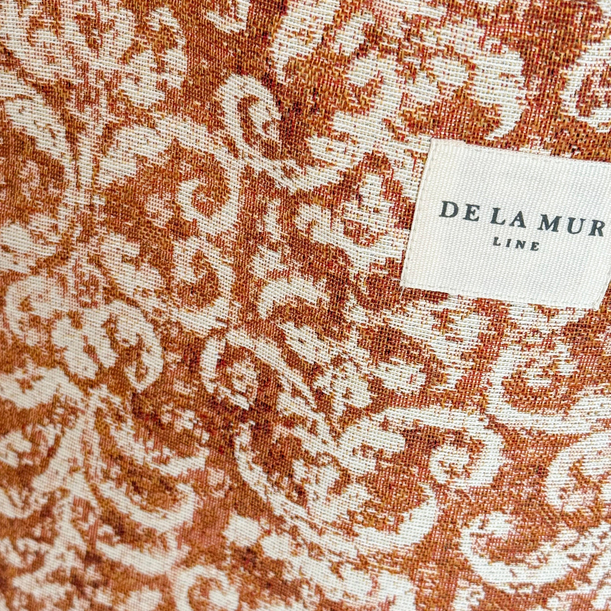 Close-up of the rust damask jacquard weave and DE LA MUR label on the Mosti tote