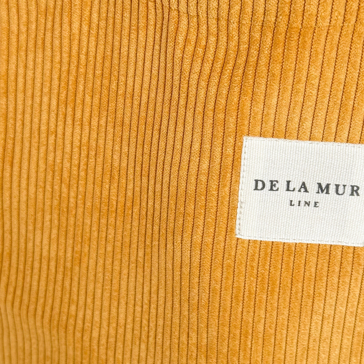 Close-up of the ribbed mustard corduroy and DE LA MUR Line label on the Taz tote