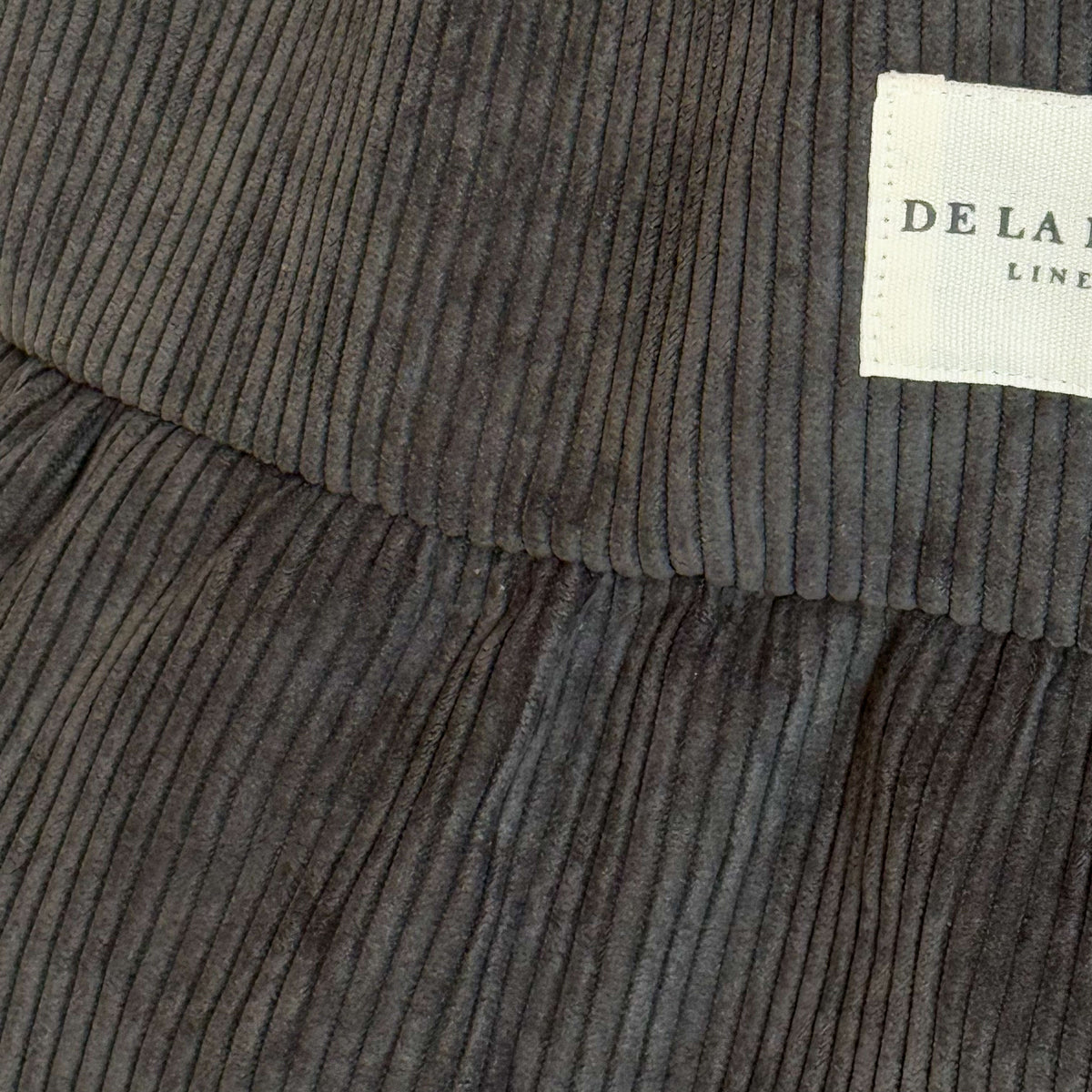 Close-up of the gray corduroy texture and DE LA MUR Line label