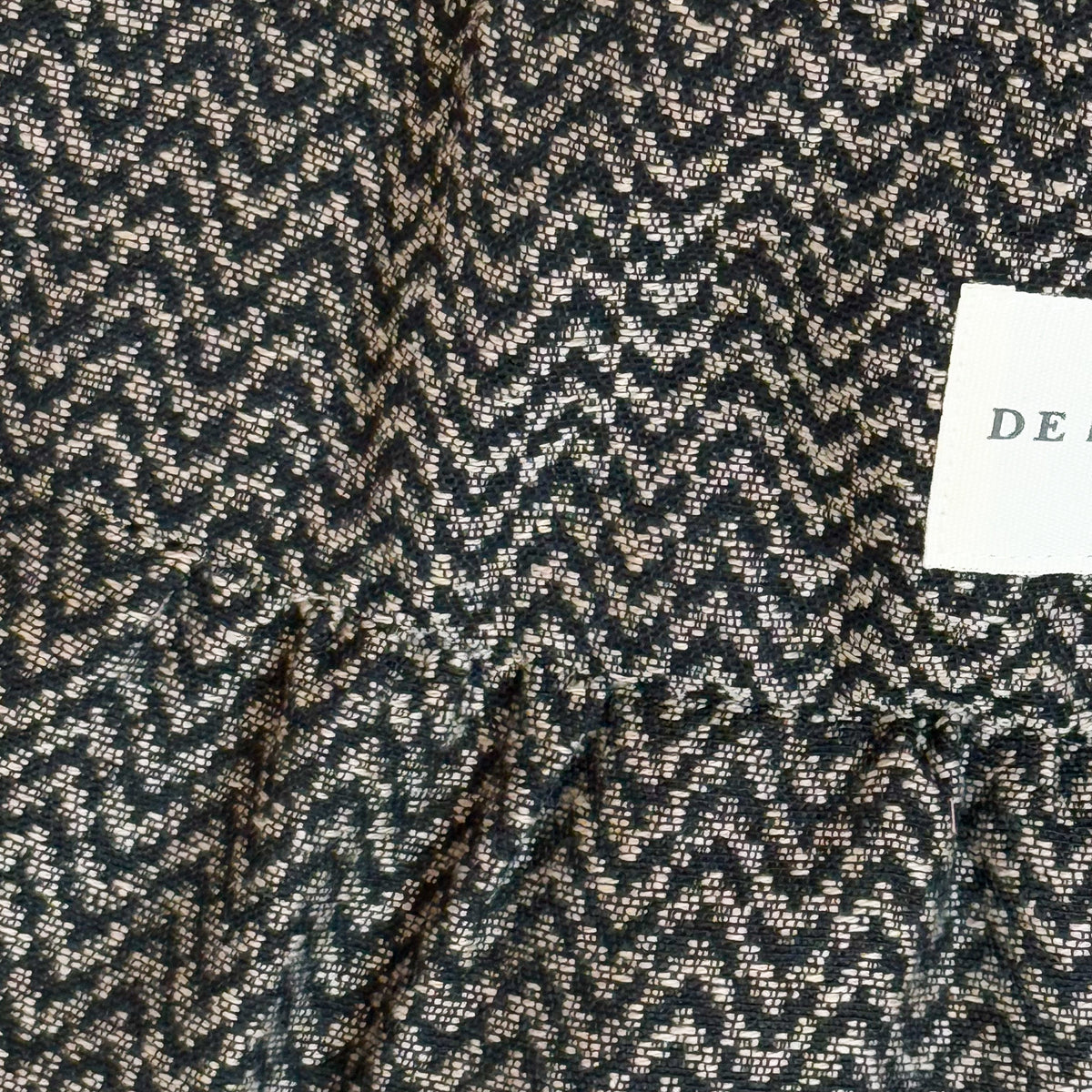 Close-up of the beige and black zigzag jacquard weave and DE LA MUR label