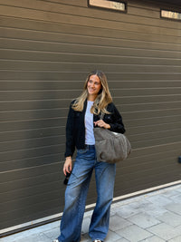 Model carrying the DE LA MUR zigzag jacquard tote bag on the shoulder outdoors