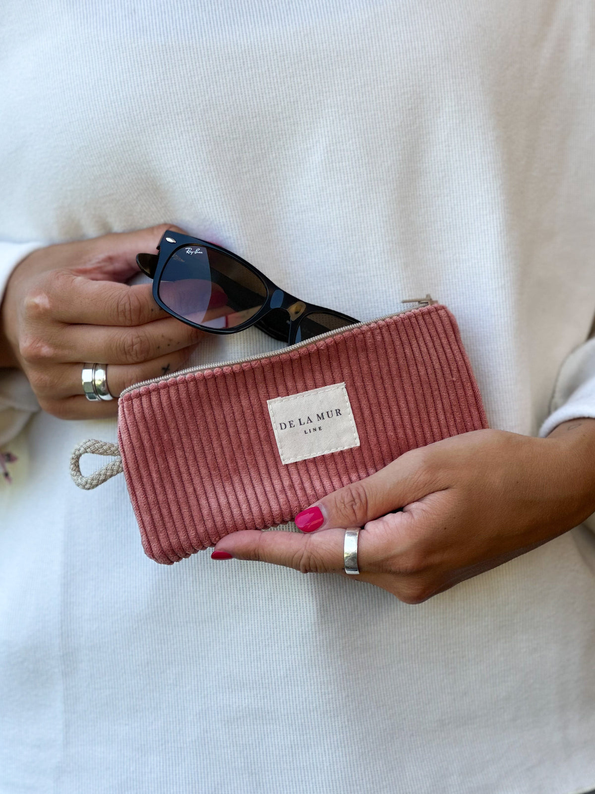Model holding DE LA MUR coral corduroy eyewear case with sunglasses