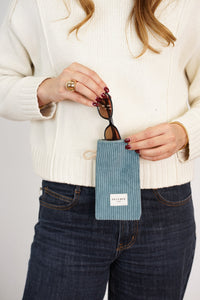 Model slipping sunglasses into DE LA MUR teal Corduroy Glasses Case