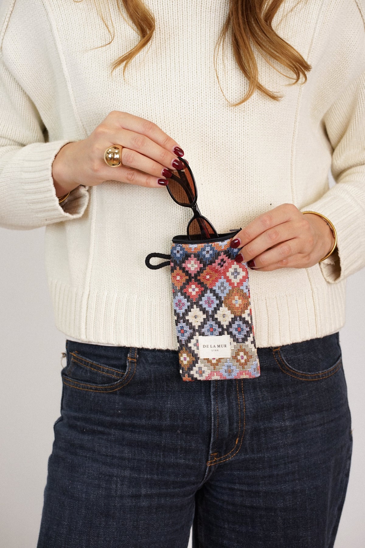 Model slipping sunglasses into the DE LA MUR geometric jacquard glasses case