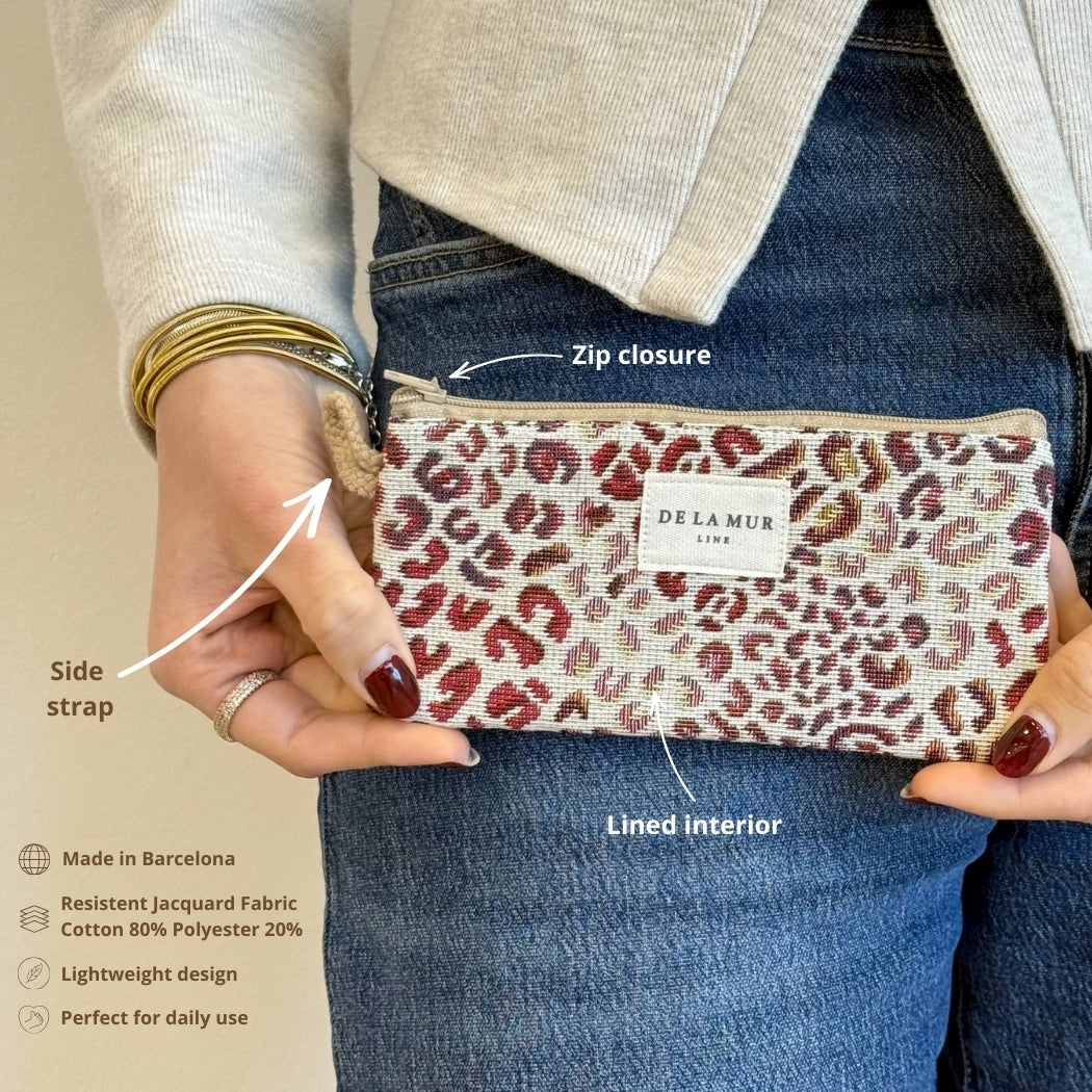 Model holding the DE LA MUR Talco leopard print eyewear case showing zip closure and strap