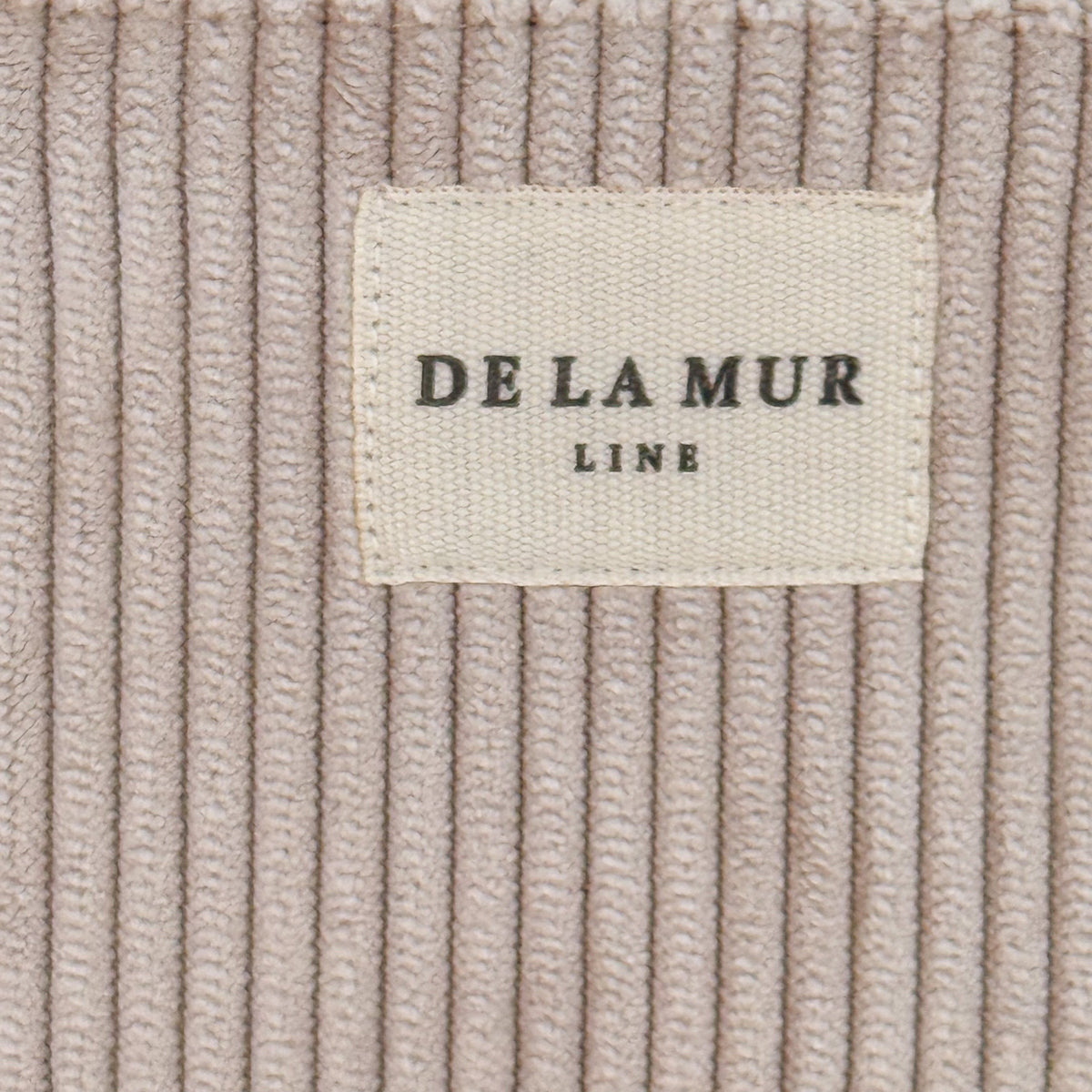 Close-up of corduroy texture and DE LA MUR Line woven label on eyewear case