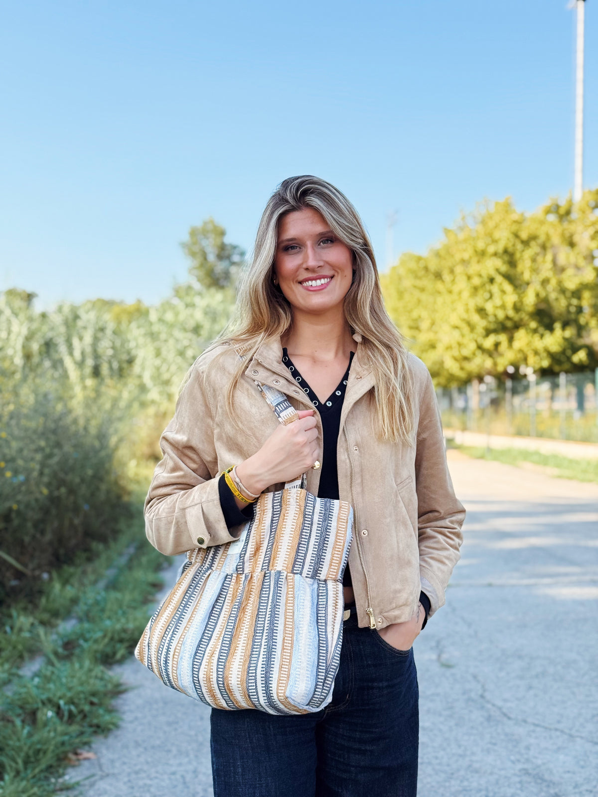 Model carrying the DE LA MUR Tron striped jacquard tote bag outdoors