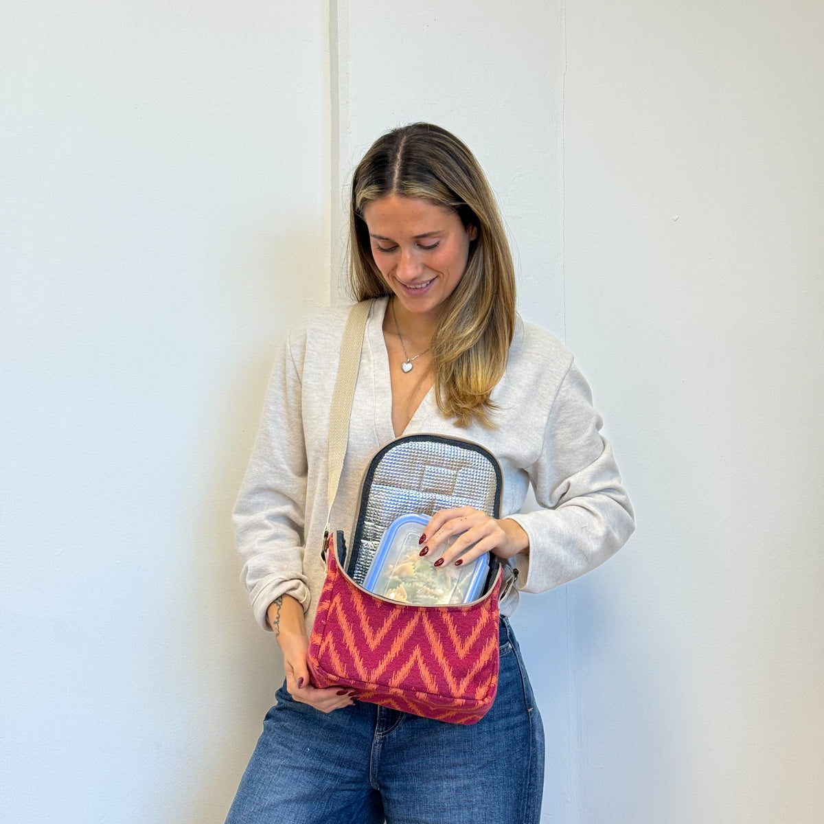 Model loading a tupperware into the DE LA MUR Fuego zigzag lunch bag