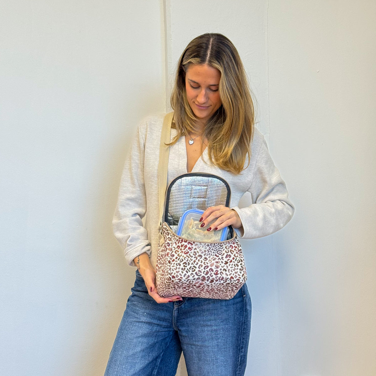 Model placing a food container in the open DE LA MUR Talco leopard lunch bag