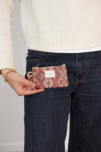 Model holding the DE LA MUR red multicolor geometric jacquard coin purse at her pocket