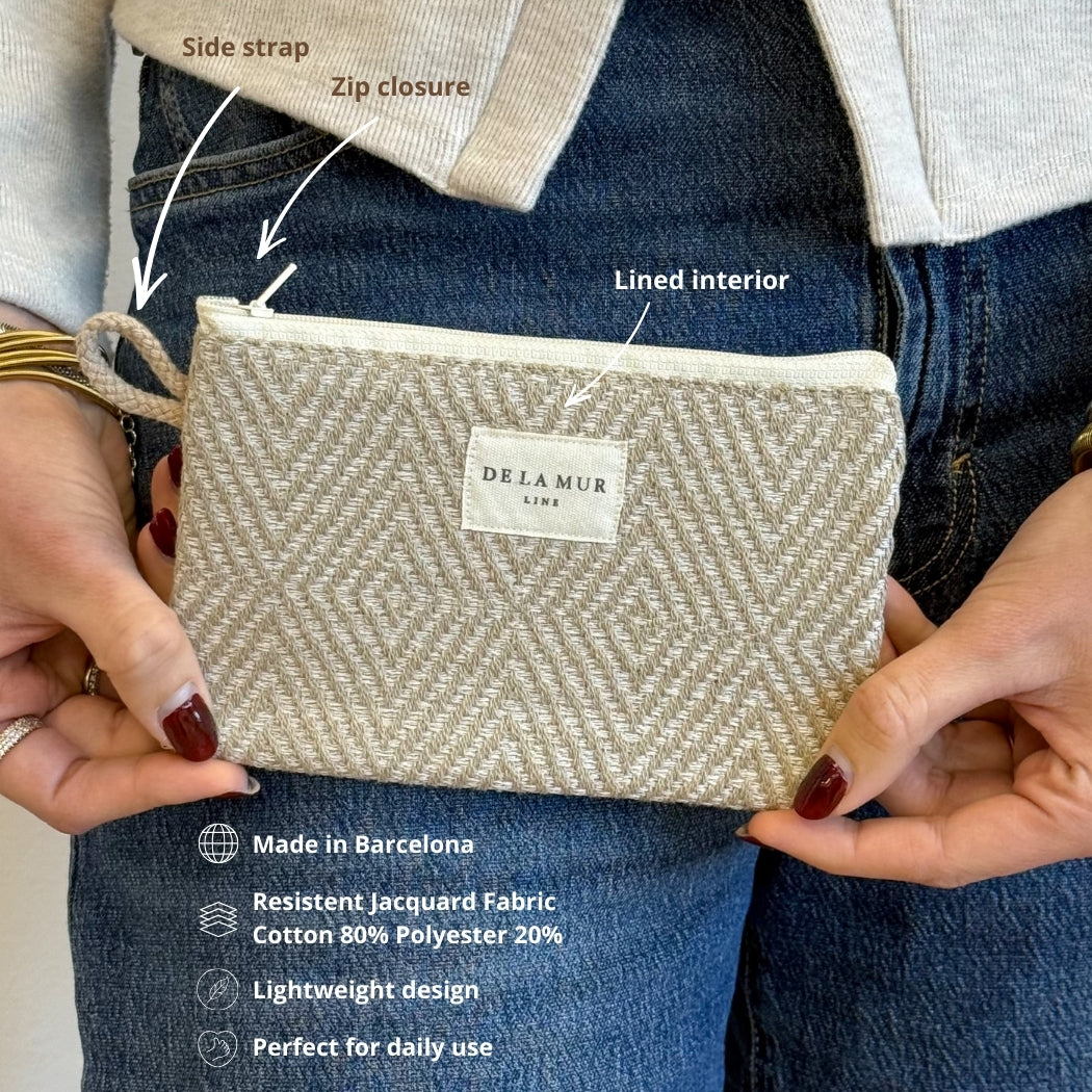 Model holding the DE LA MUR Arena makeup bag with side strap, zip and interior callouts