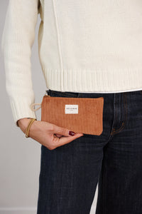 Model holding DE LA MUR terracotta corduroy makeup bag by the hip, lifestyle shot
