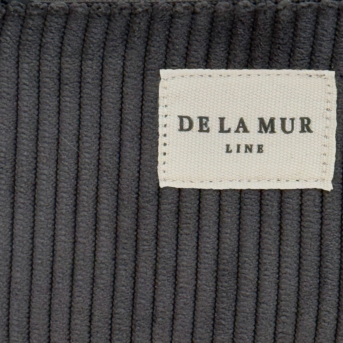 Close-up of the ribbed gray corduroy fabric and DE LA MUR Line label