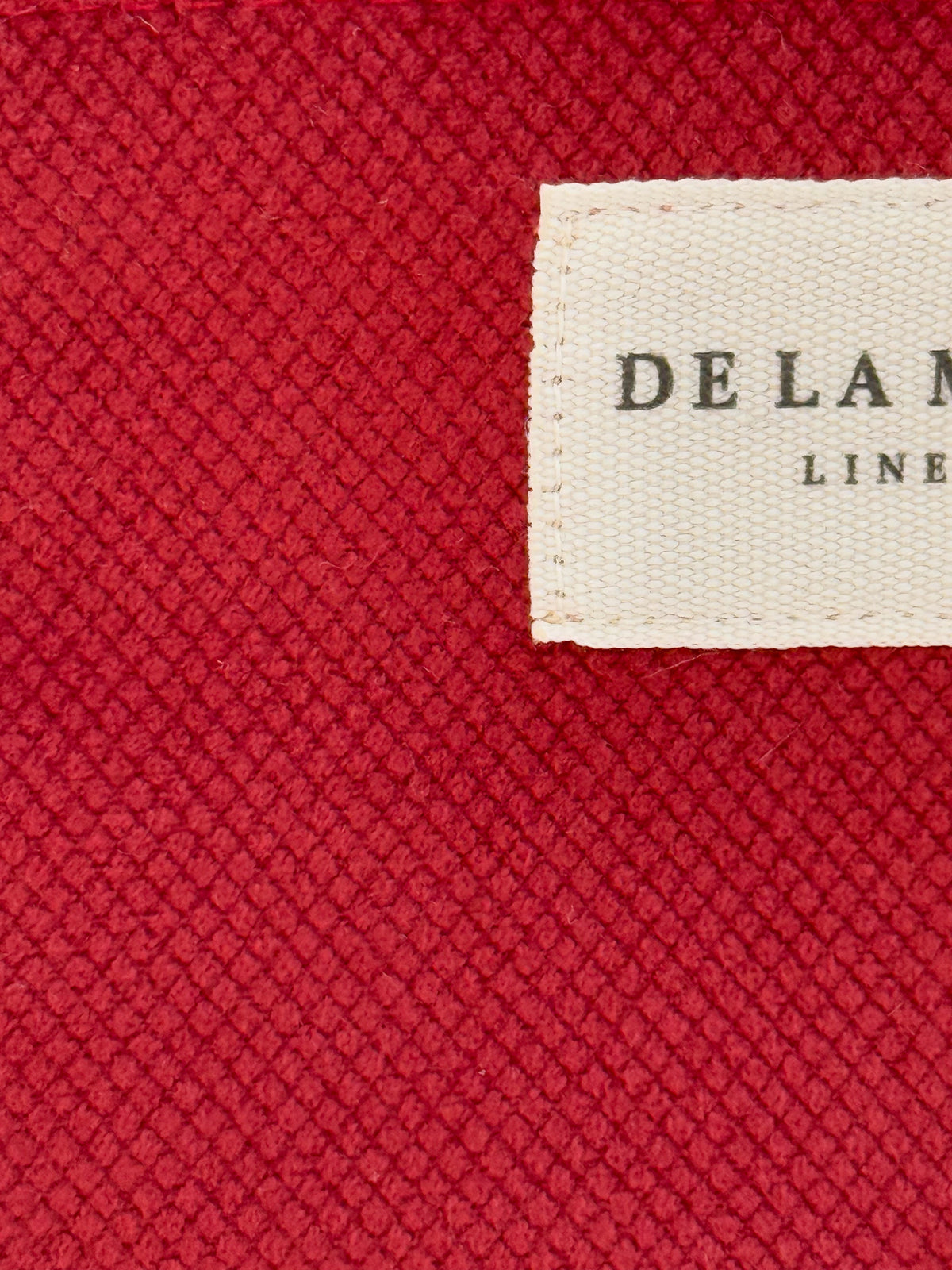Close-up of the burgundy woven fabric texture and DE LA MUR Line label