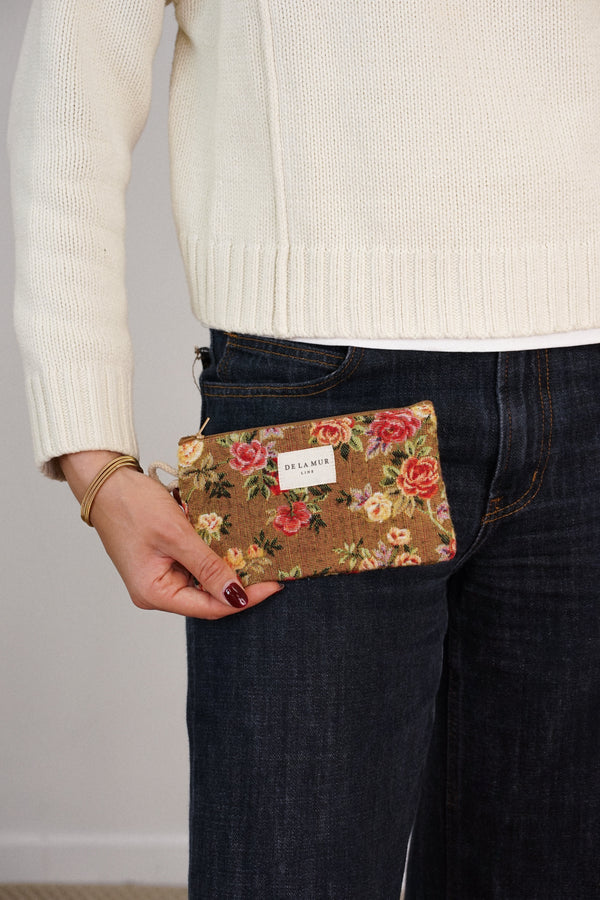 Model holding DE LA MUR mustard rose floral coin purse at the hip, lifestyle shot