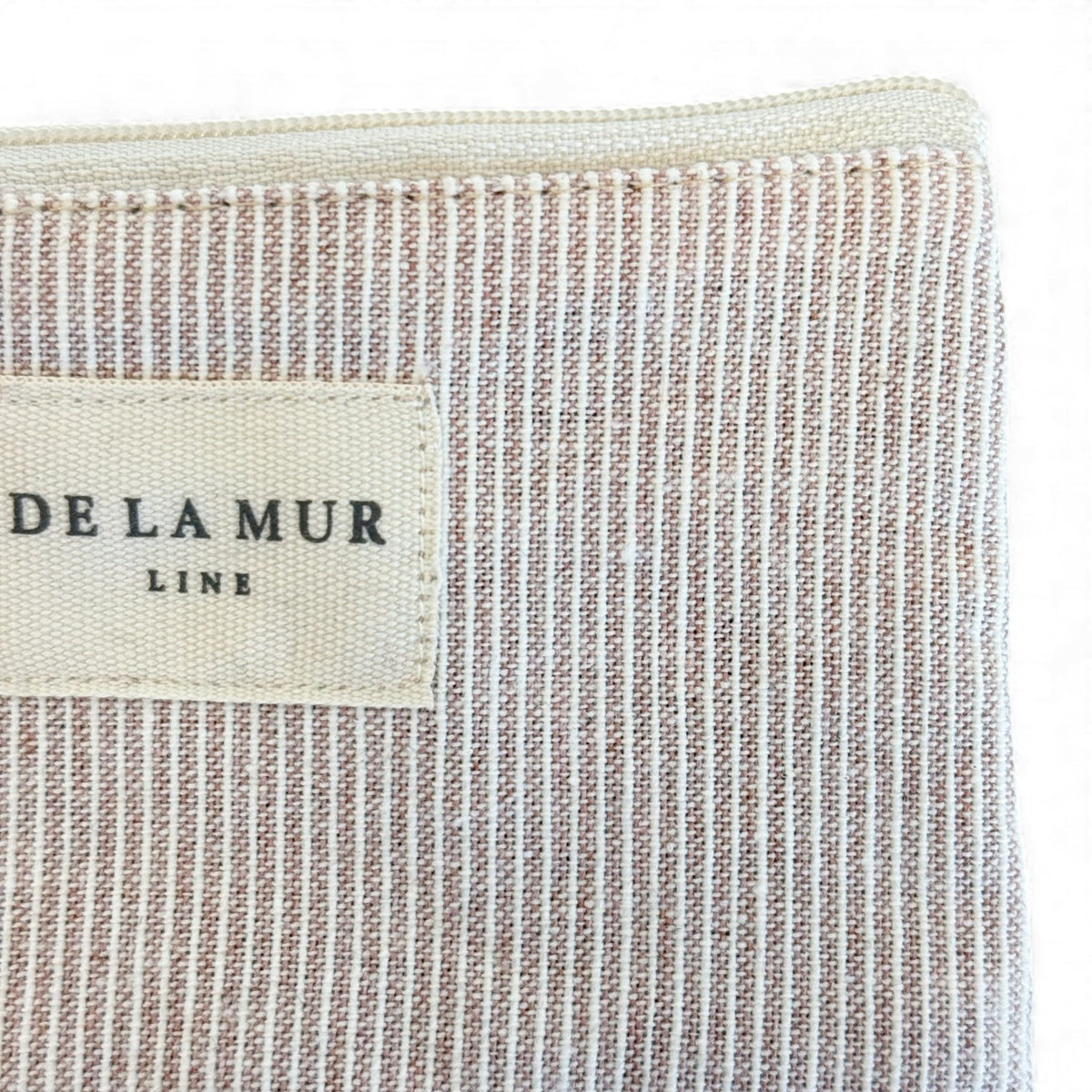 Close-up of the DE LA MUR Line label on the Ibi textured stripe makeup bag