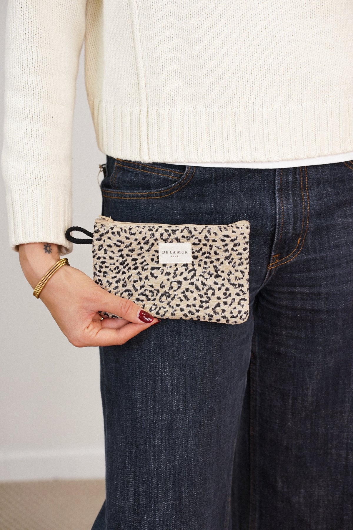 Model holding the beige and black leopard jacquard DE LA MUR Koto makeup bag, lifestyle shot