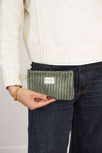 Model holding the olive green DE LA MUR Musgo corduroy makeup bag / coin purse