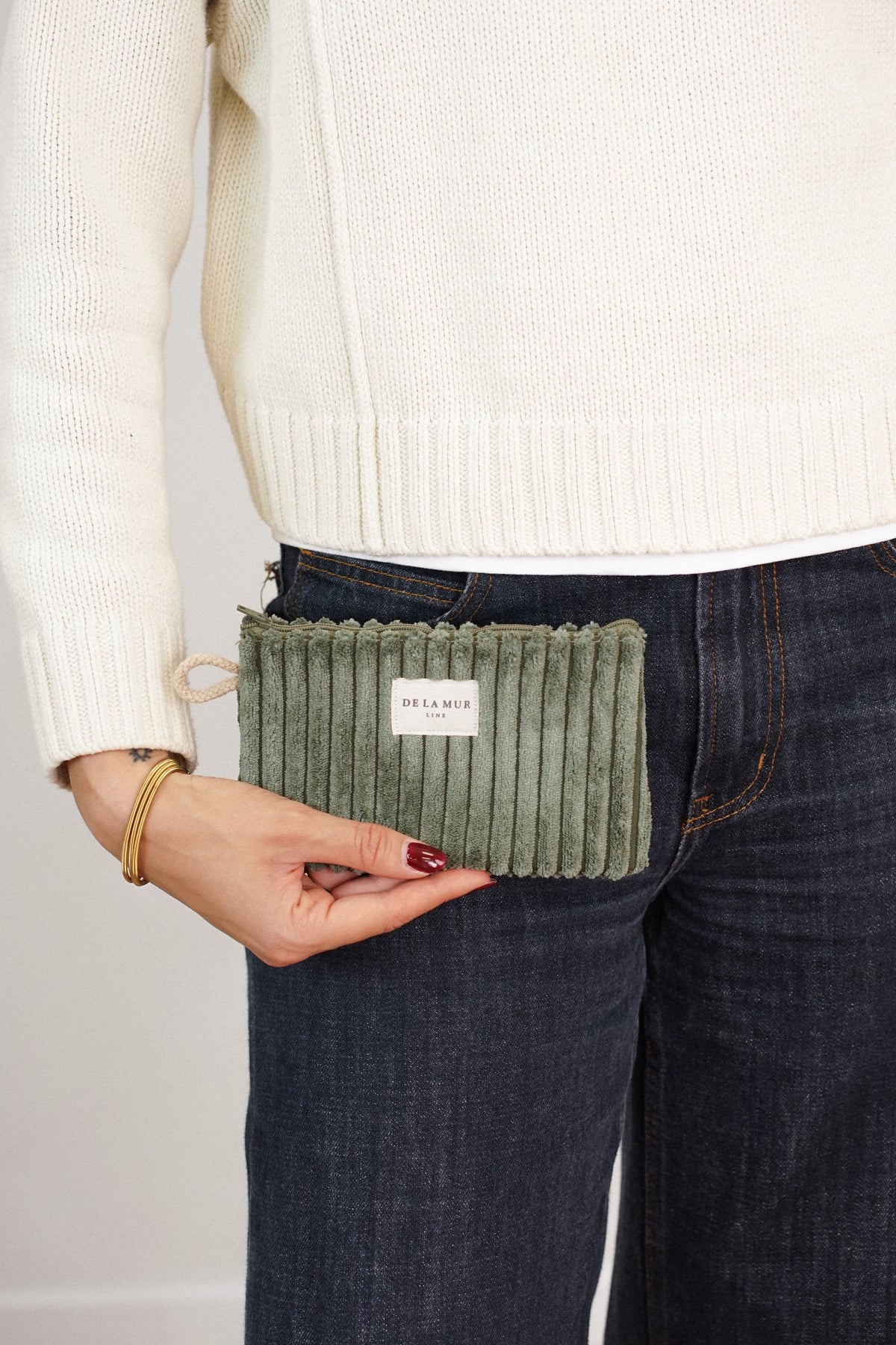 Model holding the olive green DE LA MUR Musgo corduroy makeup bag / coin purse