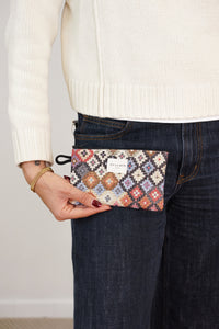 Model holding DE LA MUR multicolor geometric jacquard coin purse at the hip, lifestyle shot