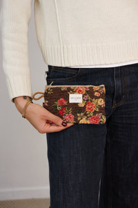 Model holding the brown floral jacquard DE LA MUR Pepi makeup bag / coin purse