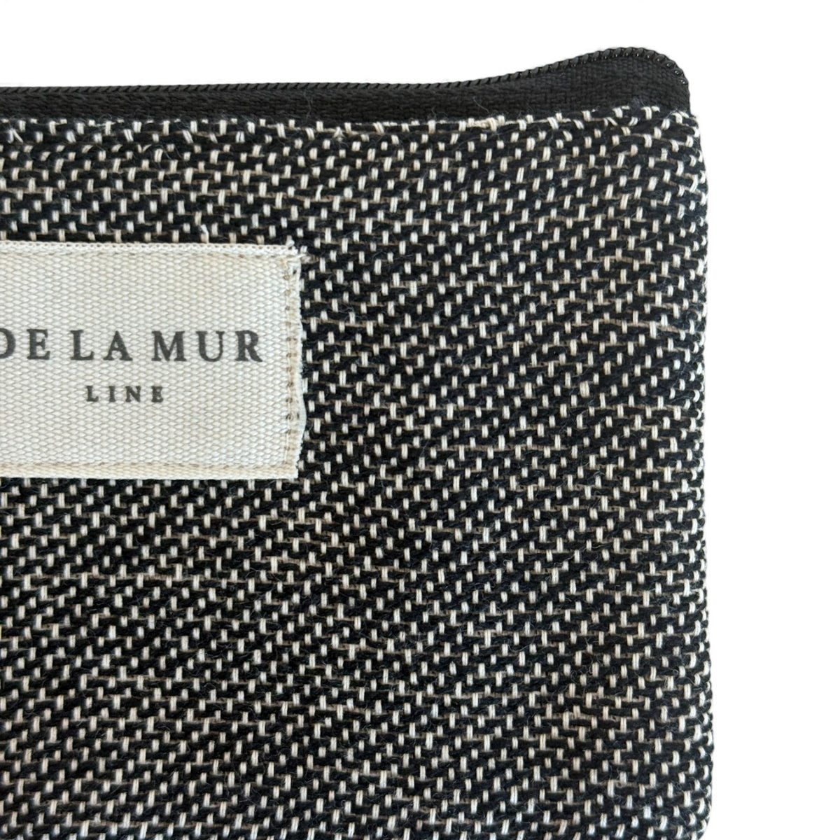 Close-up of DE LA MUR Line label on the Sinay woven black-and-natural bag