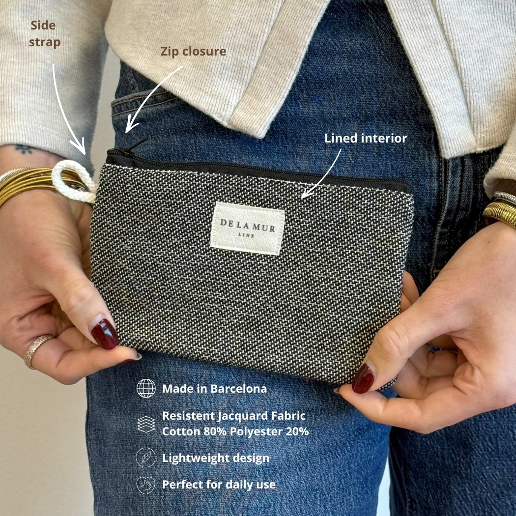 Hands holding DE LA MUR Sinay pouch, infographic of strap, zip and lined interior