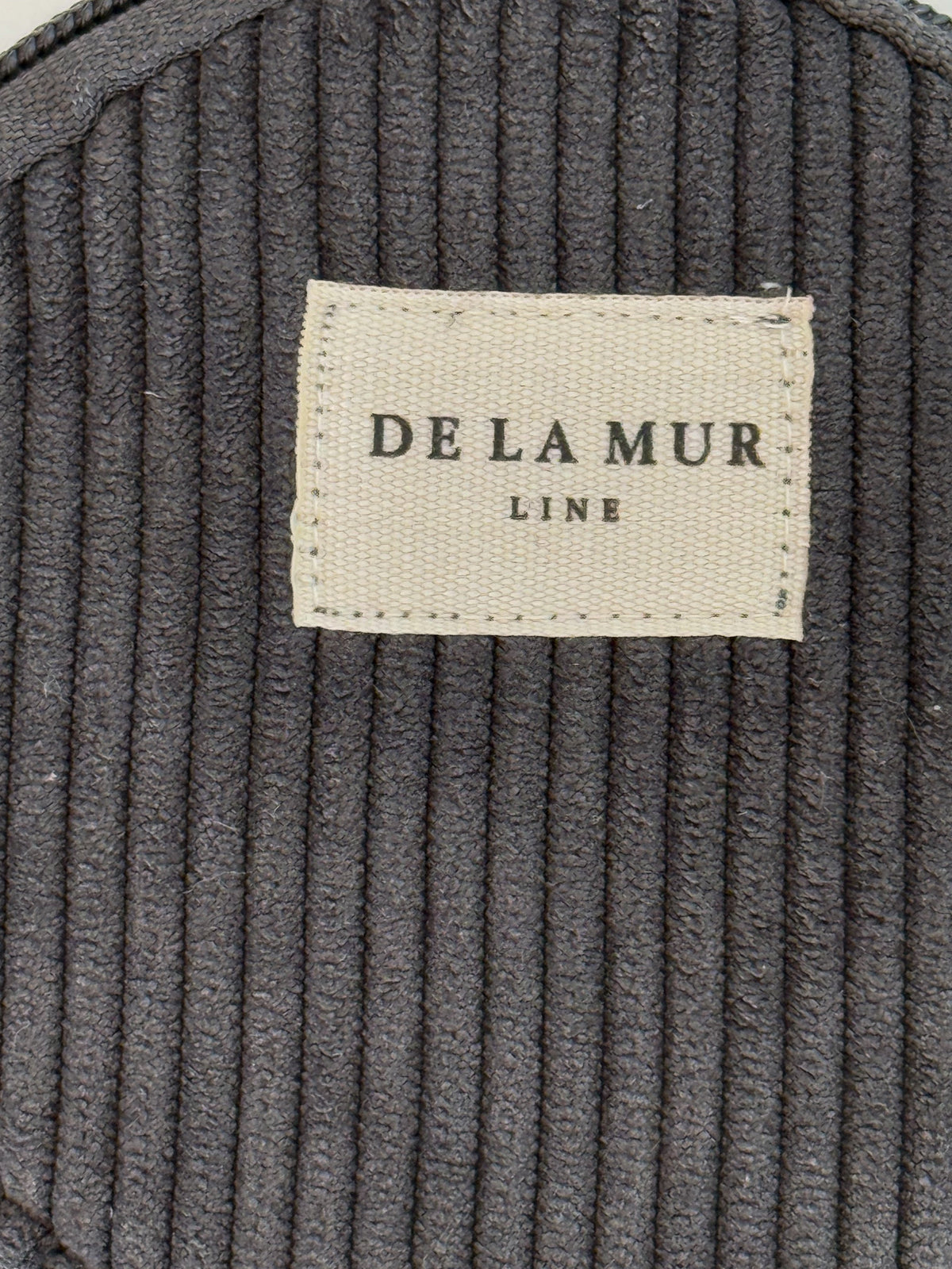 Close-up of charcoal corduroy fabric and DE LA MUR Line woven label