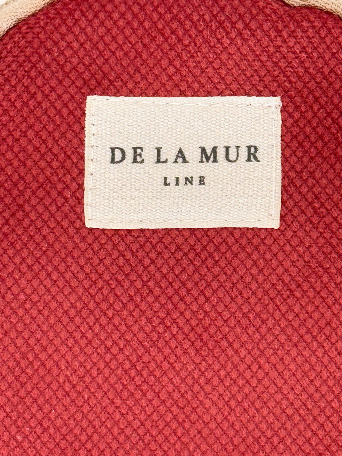 Close-up of burgundy textured weave and DE LA MUR Line label, Bore purse