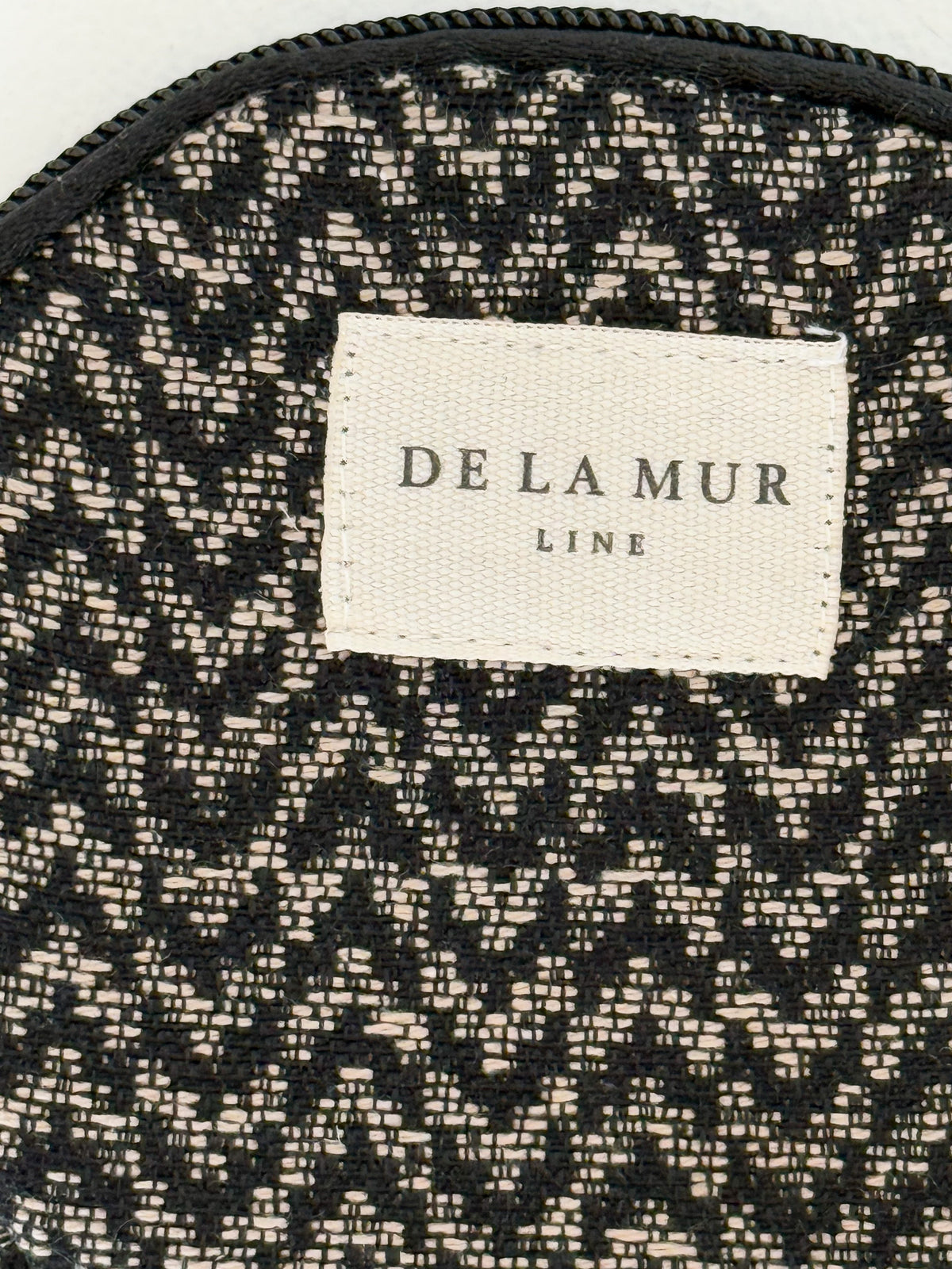 Close-up of the black and beige jacquard fabric and DE LA MUR Line label on the coin purse
