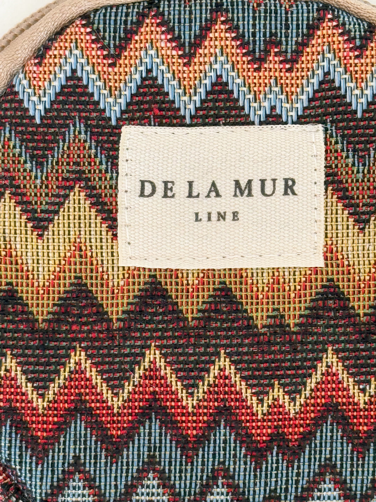 Close-up of the multicolor zigzag jacquard fabric and DE LA MUR Line label
