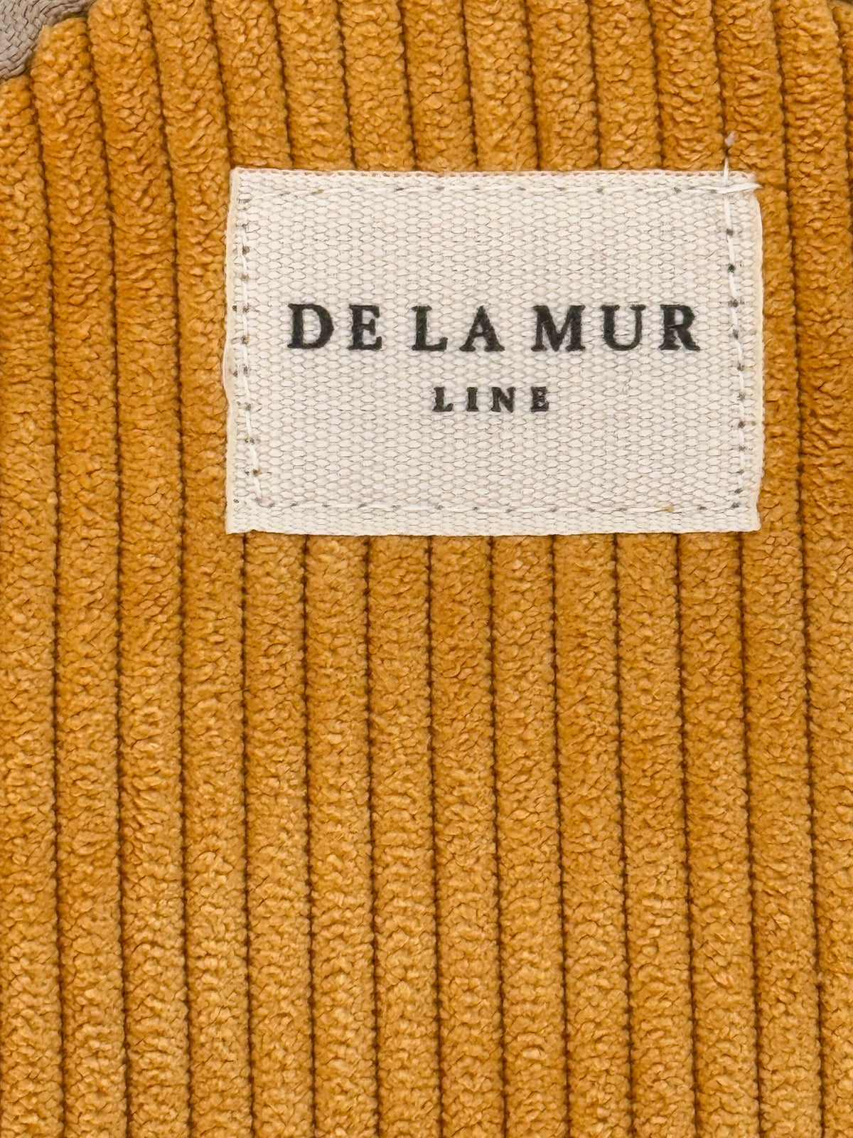 Close-up of the mustard corduroy texture and DE LA MUR Line label