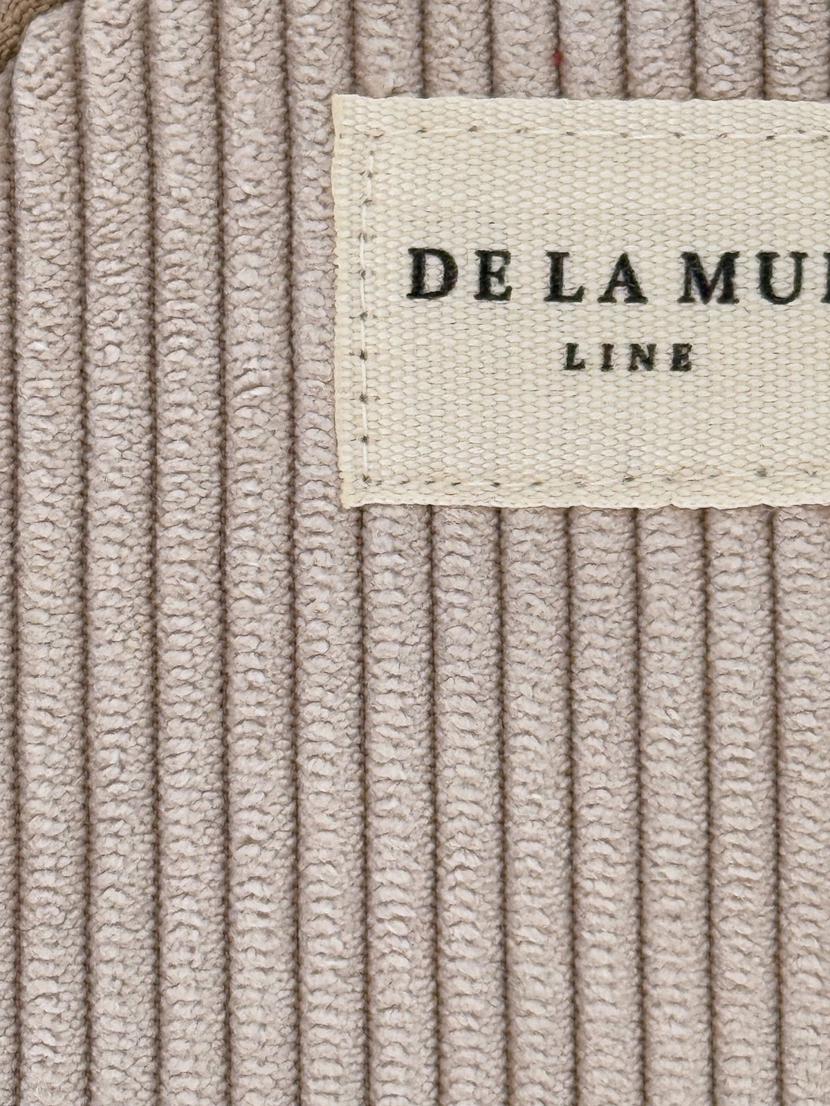 Close-up of taupe corduroy texture and DE LA MUR Line label detail