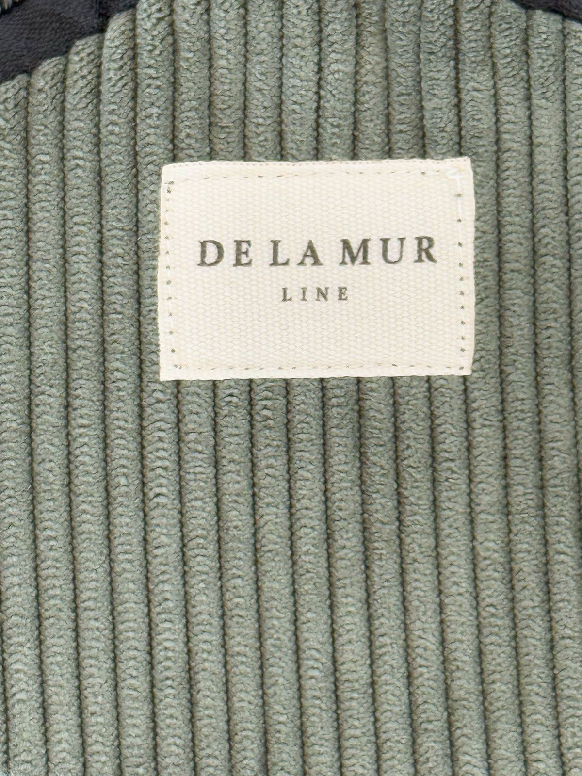 Close-up of the green corduroy texture and DE LA MUR Line label