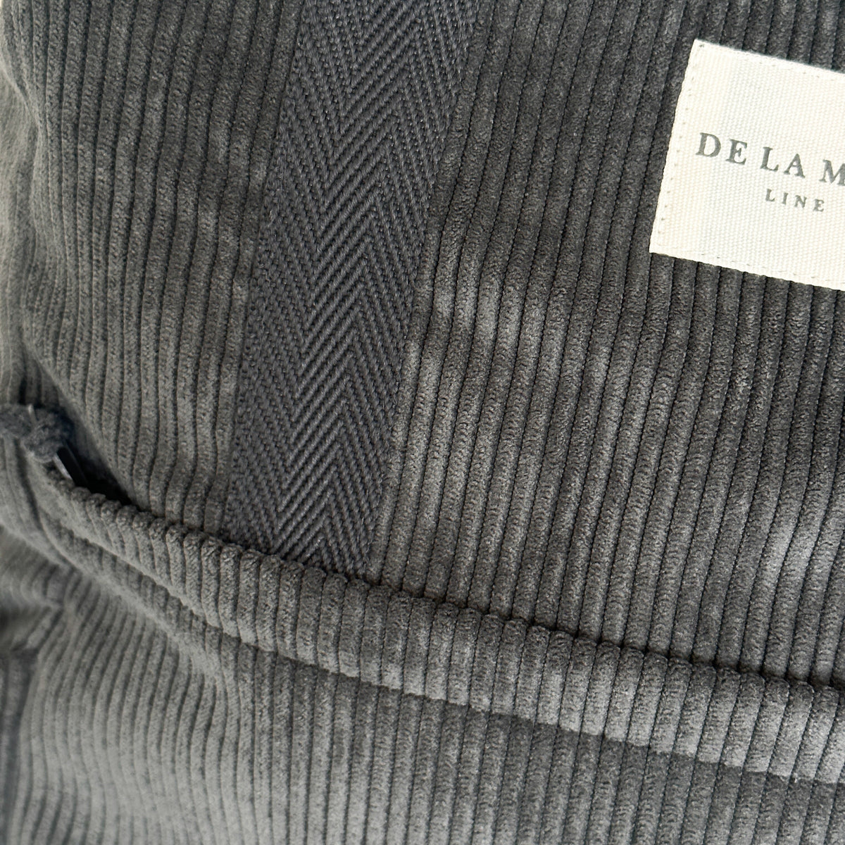 Close-up of the gray corduroy texture and herringbone strap on the DE LA MUR backpack