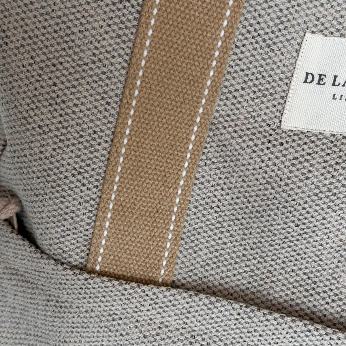 Close-up of the DE LA MUR Sydney woven fabric, stitched strap and Line label