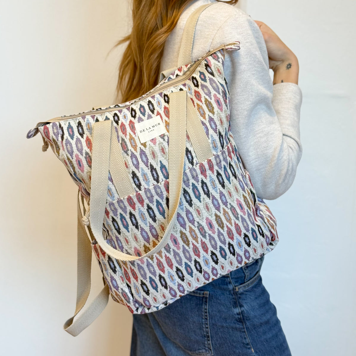 Model wearing the DE LA MUR Urban backpack tote on her shoulder, back view