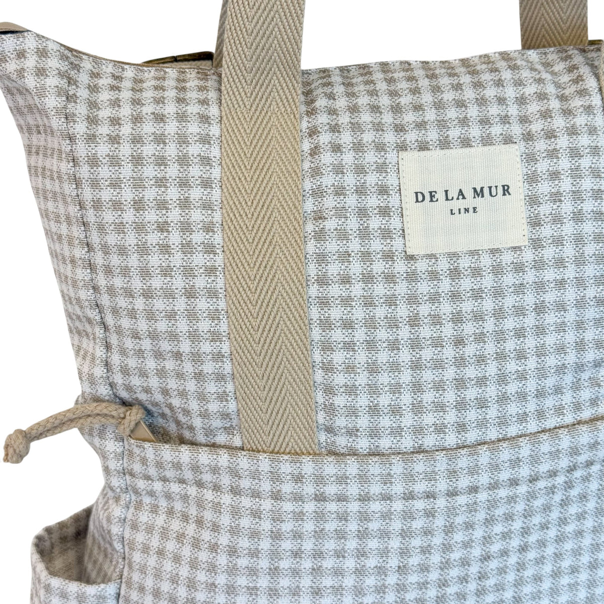 Close-up of the DE LA MUR Line label on the beige gingham jacquard fabric