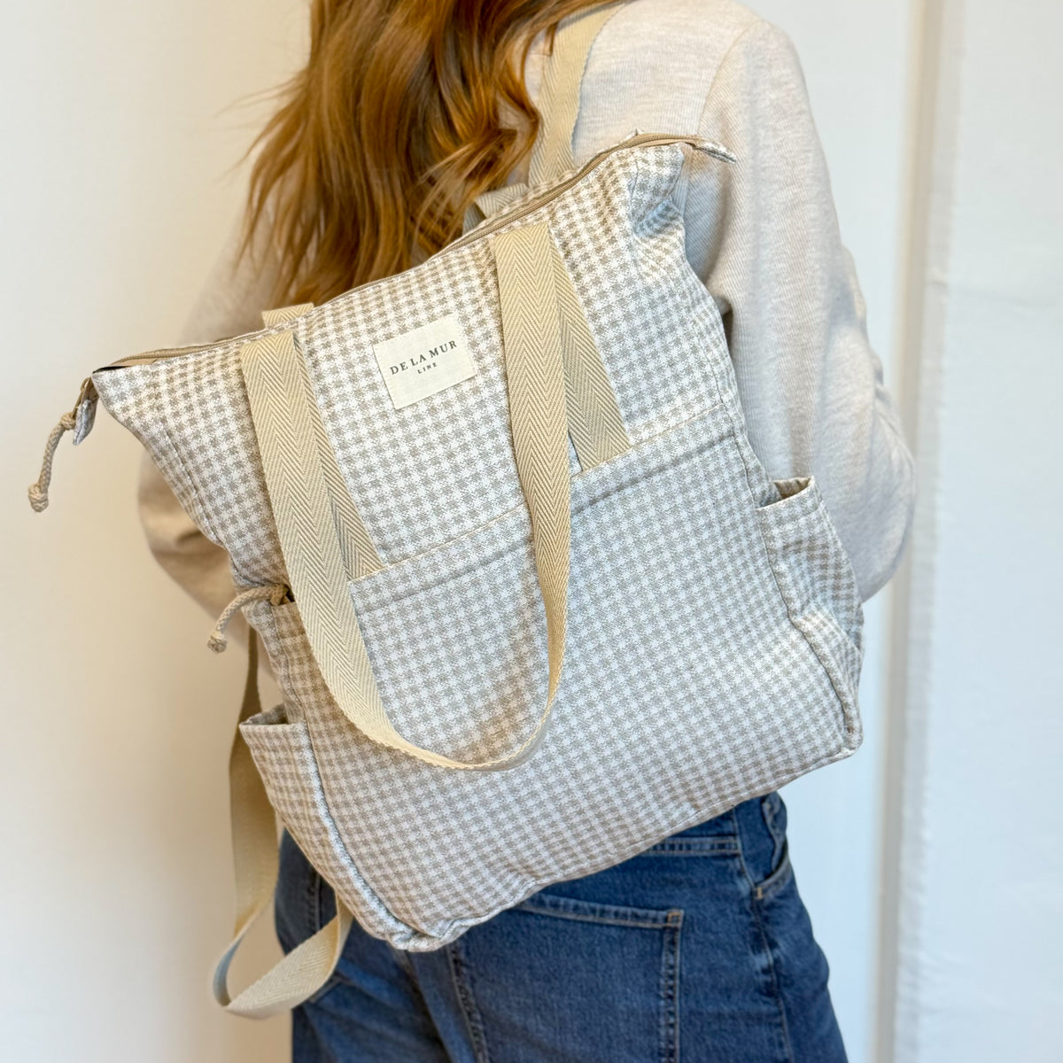 Model wearing the DE LA MUR Vison gingham backpack tote, back view