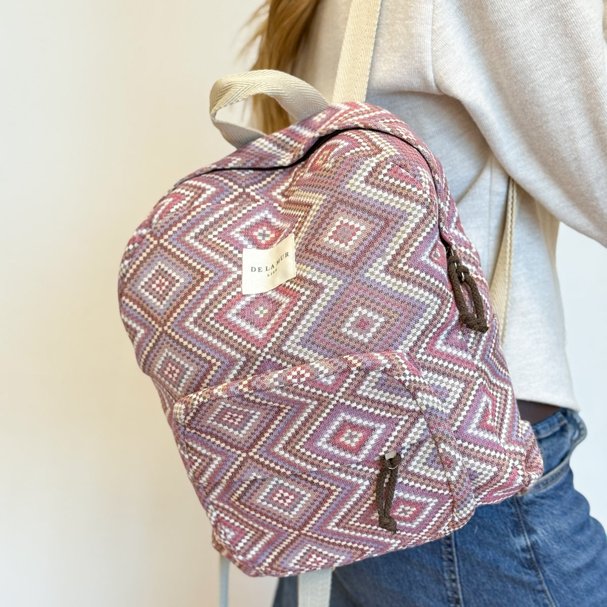 Model carrying the DE LA MUR Nana diamond jacquard backpack, side view
