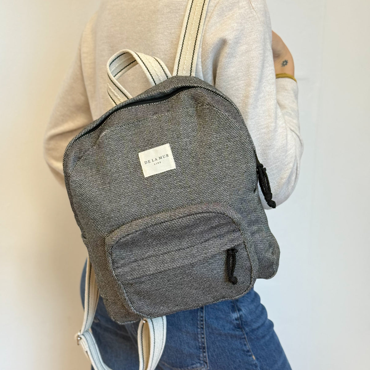 Model carrying the DE LA MUR Sinay herringbone backpack, side view