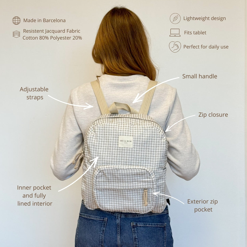 Model wearing the DE LA MUR Vison gingham backpack with features infographic, back view
