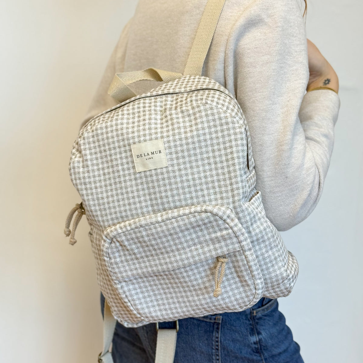 Model carrying the DE LA MUR Vison gingham backpack, side view