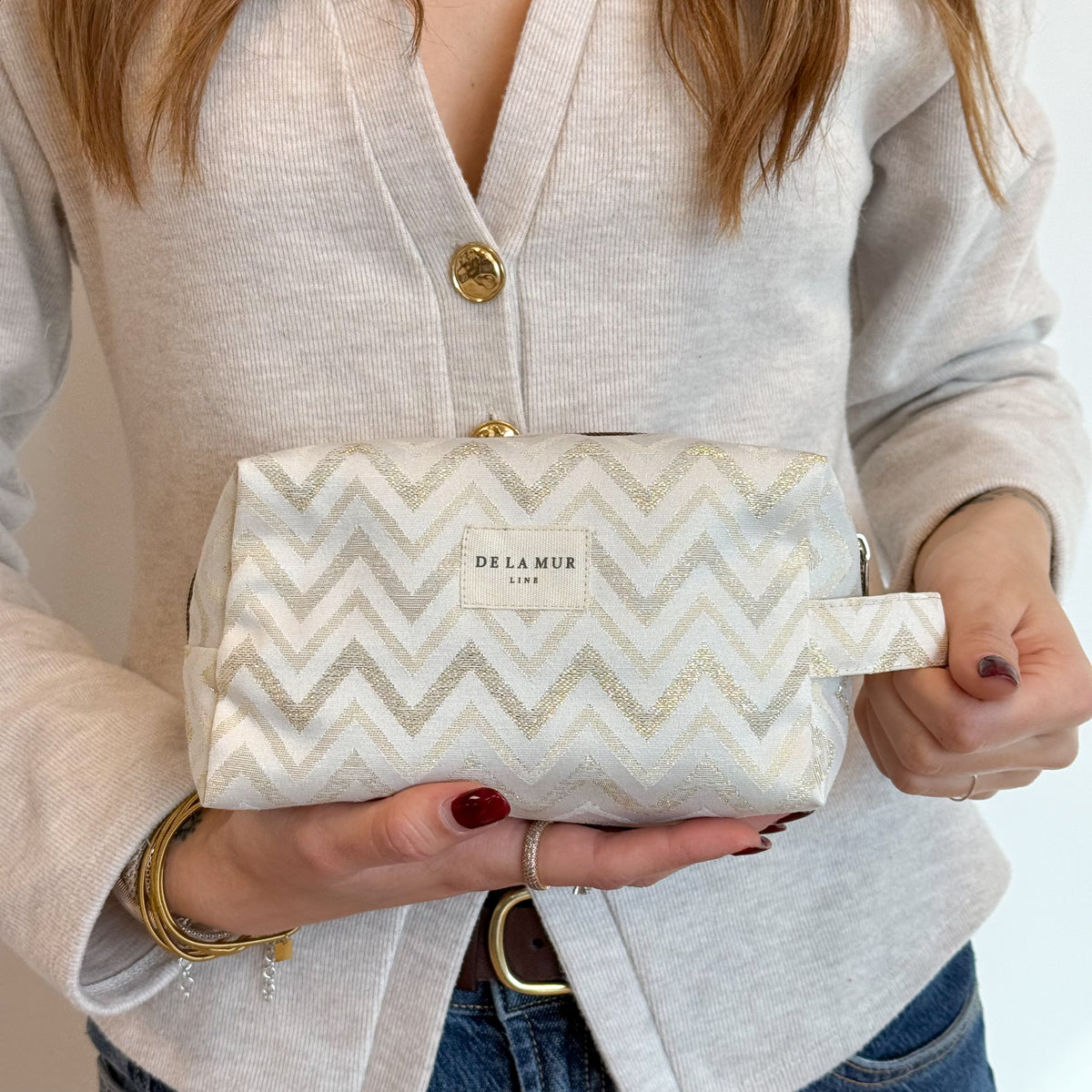 Close-up of the gold lurex zigzag jacquard fabric on the DE LA MUR makeup bag